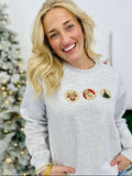 Person wearing a Ash sweatshirt with Christmas-themed cookies in front of a decorated Christmas tree.