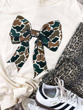 White sweatshirt with a large camouflage bow, leopard print pants, and Adidas sneakers on a white background.