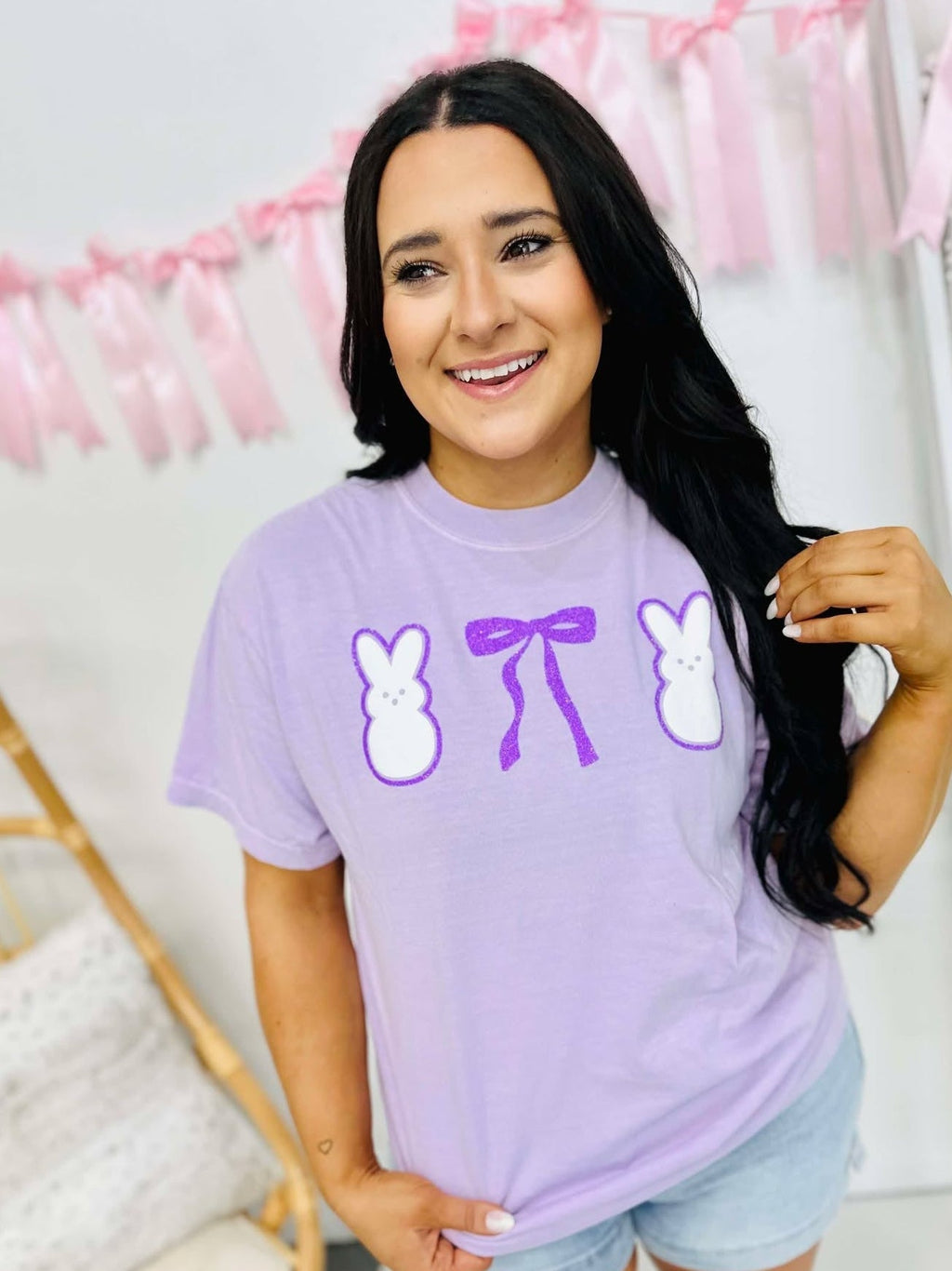 Woman wearing a purple t-shirt with graphic designs in a home setting