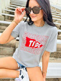 Person wearing a gray t-shirt with 'Gameday Tide' text and logo, sitting outdoors.