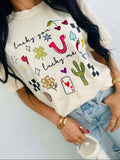 Person wearing a white t-shirt with colorful lucky you lucky me western cowboy graphics and text.