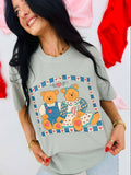 Woman wearing a light gray t-shirt with teddy bear design, standing against a colorful background.