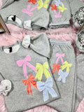 Gray sweatshirt and pants set with colorful bows on a pink surface.