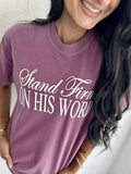 A person wearing a purple t-shirt with the text 'Stand Firm ON HIS WORD' printed in white.