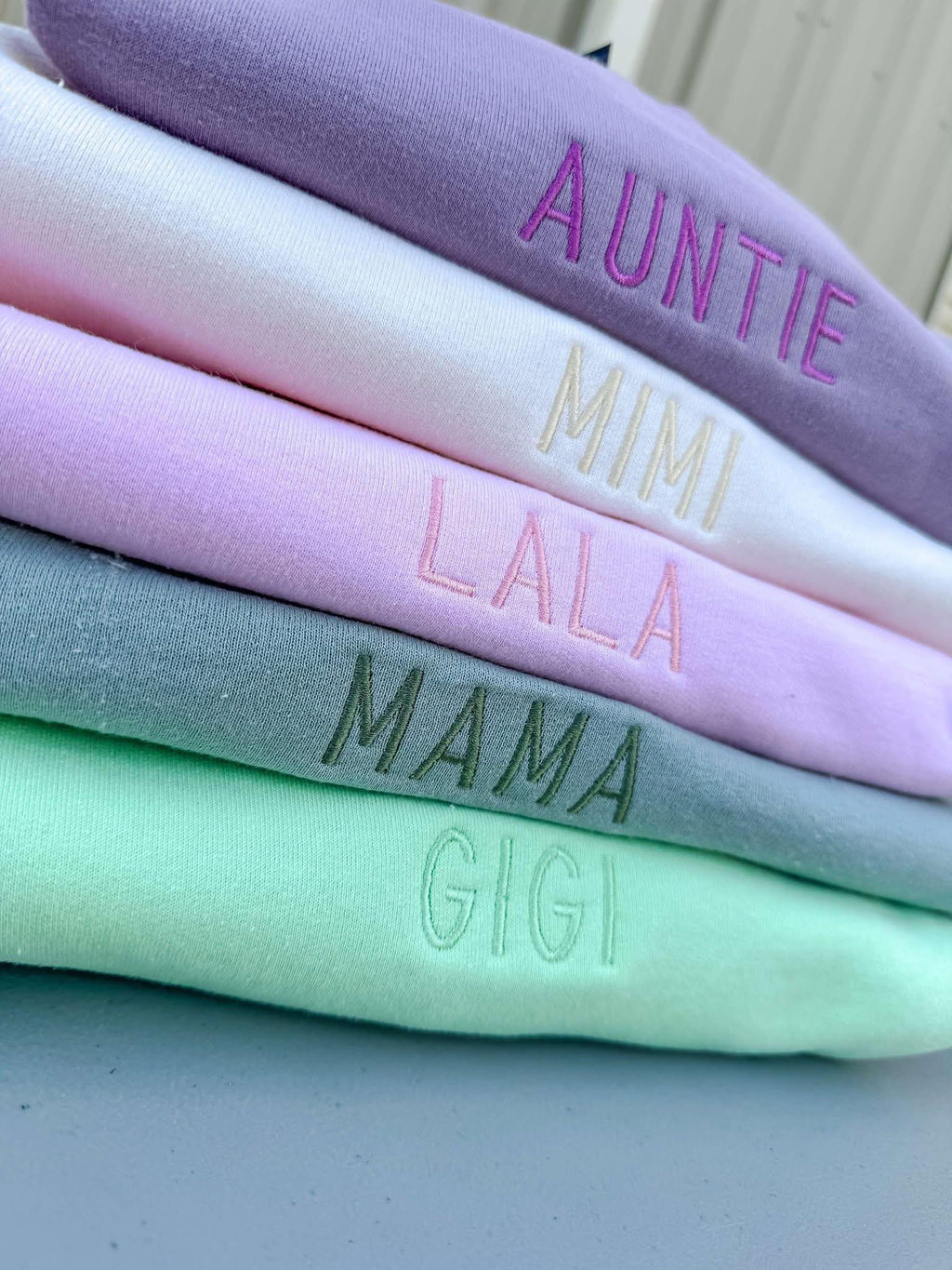 Stack of colorful fabric swatches with embroidered text on a neutral background