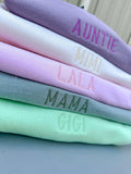 Stack of colorful fabric swatches with embroidered text on a neutral background