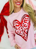 Person wearing a pink sweatshirt with a red leo metallic heart design on a white background