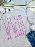Gray sweatshirt with pink and green stripe WWJD text design on a white surface