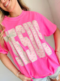 Woman wearing a pink t-shirt with decorative JESUS text with cross charm and graphics.