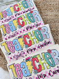 Colorful 'Teacher' nameplates with personalized text on a textured surface.