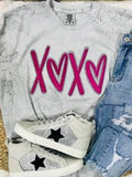A Smoke Comfort Color t-shirt with pink 'XOXO' heart applique, paired with blue denim jeans and white sneakers with a star pattern.