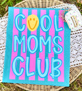 Canvas with 'Cool Moms Club' text on a striped background, placed on a woven surface.
